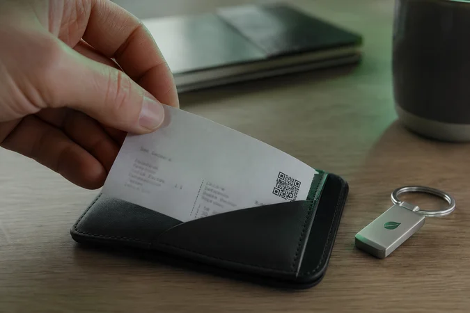 Mano alza recibo con QR desde billetera oscura llavero logo