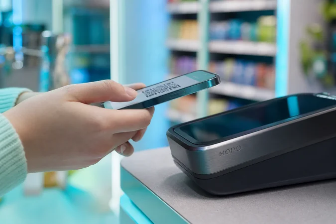 Manos sosteniendo un smartphone pagando con MODO en caja moderna