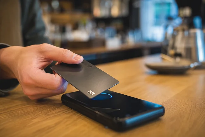 Persona sostiene tarjeta de pago sin contacto junto al teléfono