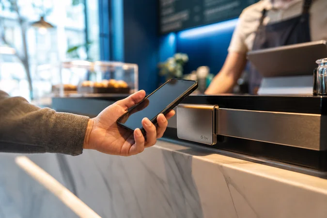 Persona sostiene teléfono junto a wallet metalico con Google Pay
