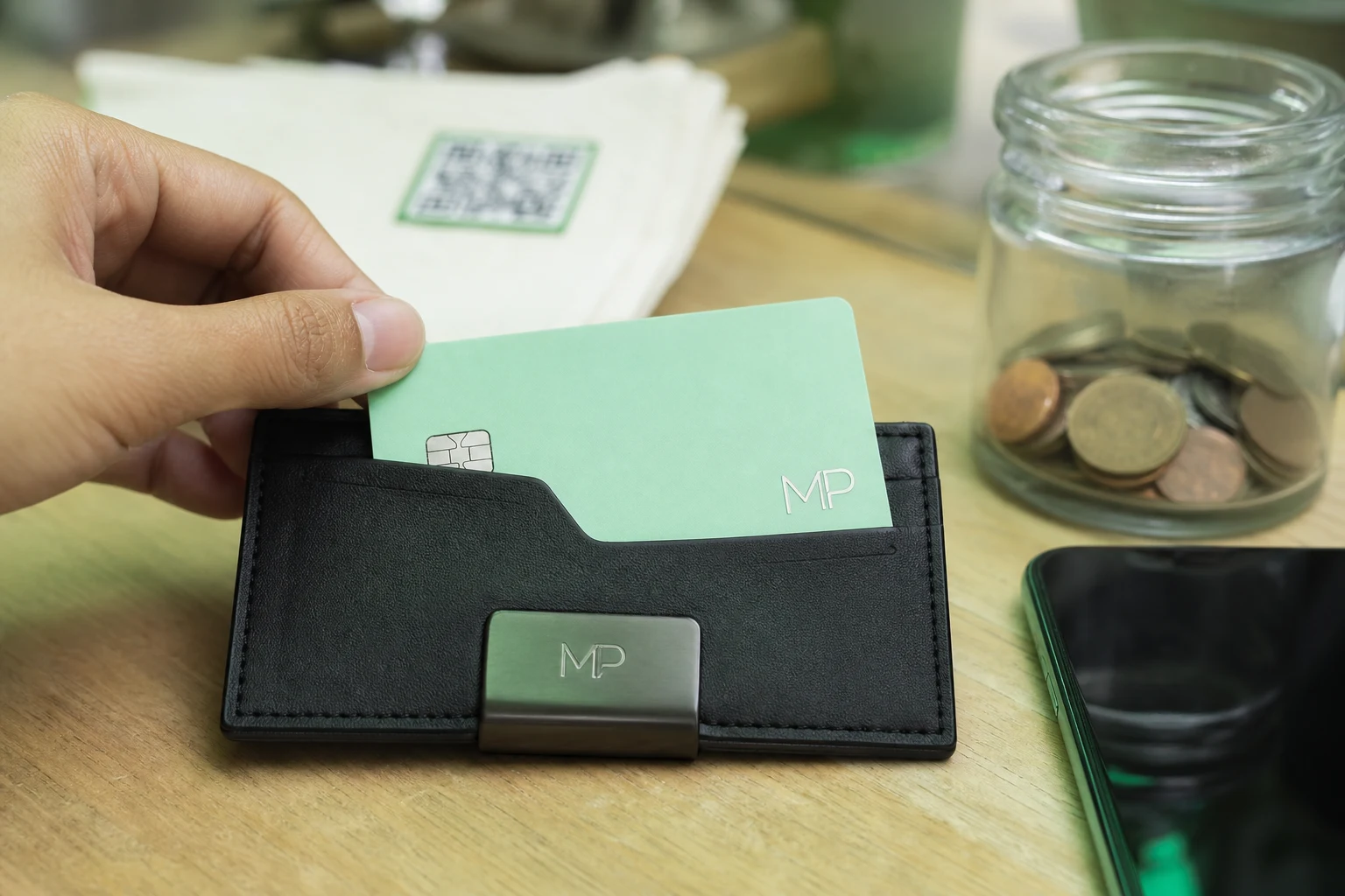 Cartera negra minimalista abierta sobre mesa café tarjeta verde MP logotipo